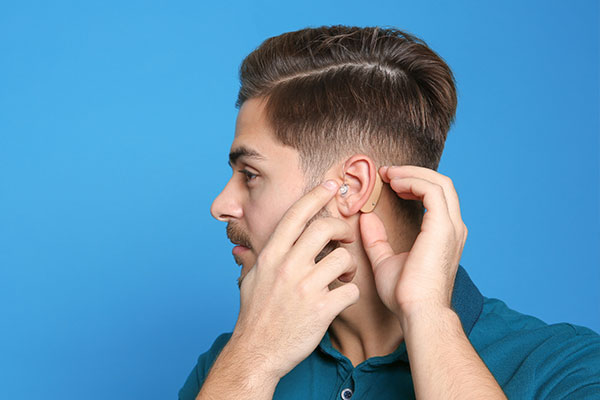 Young man checking on his hearing aid.
